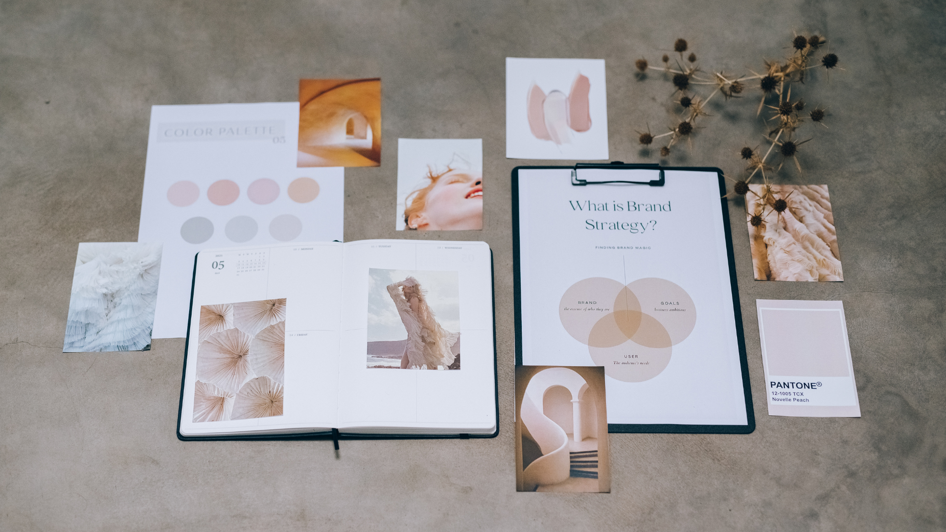 A flat lay of branding materials and aesthetic inspiration items on a gray surface.